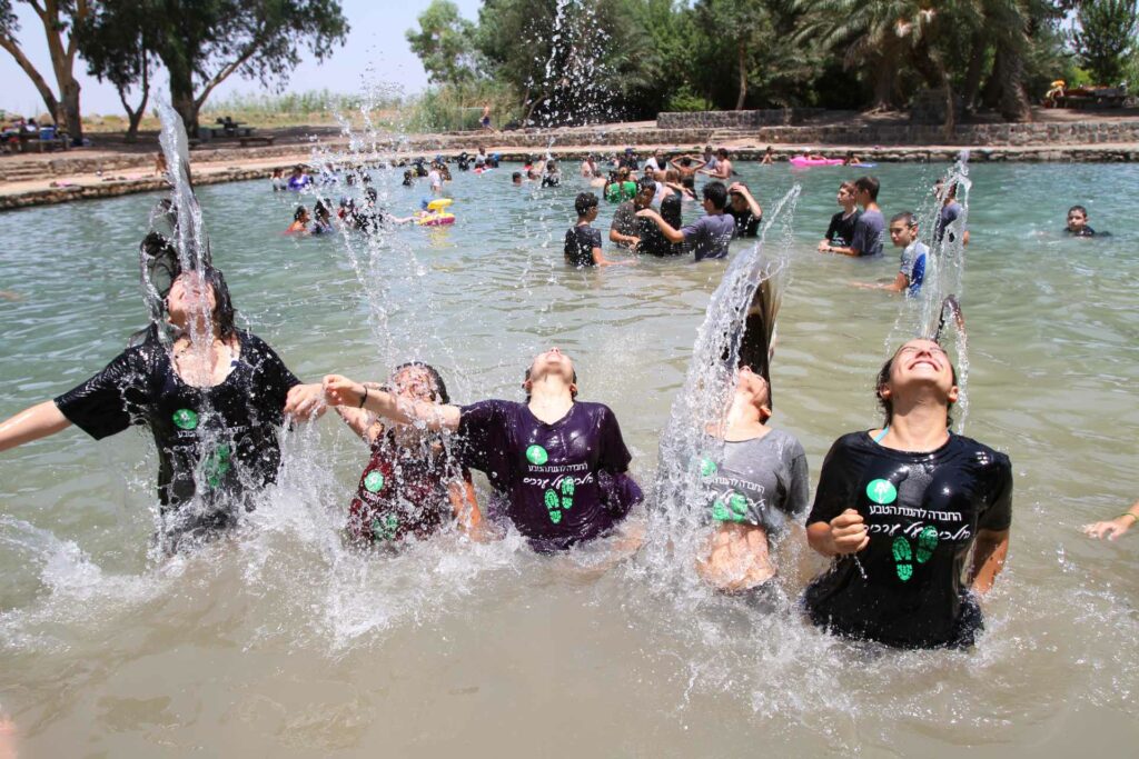 בנות בבריכה בטבע משפריצות מים במחנה קיץ 