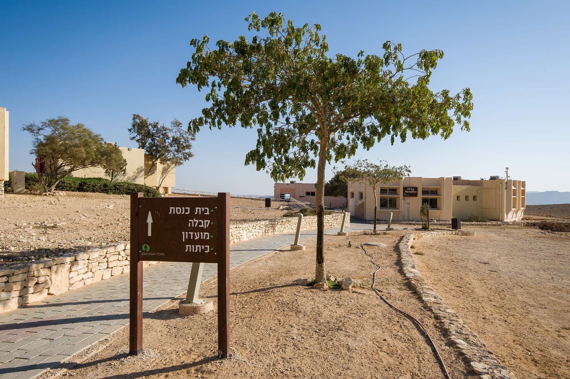 שלט בכניסה לבית ספר שדה הר הנגב ולידו שביל המוביל לבית הספר