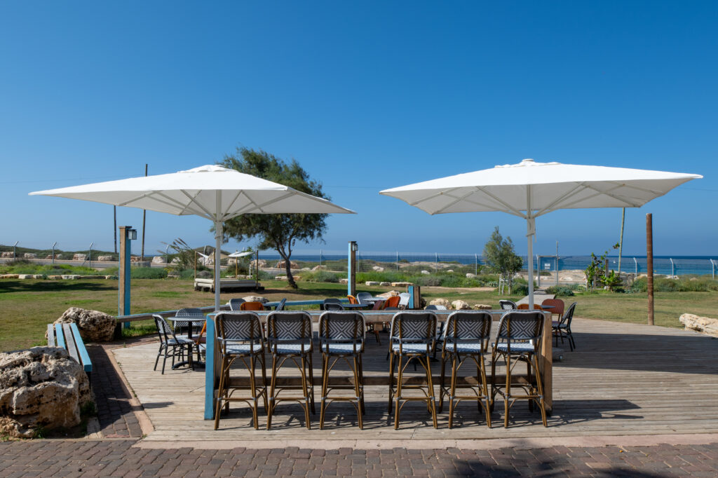 בר עם כסאות, נוף לים, ברחבה מחוץ לחדר האוכל באכזיב. מקומות ישיבה ושמשיות עם נוף לים 