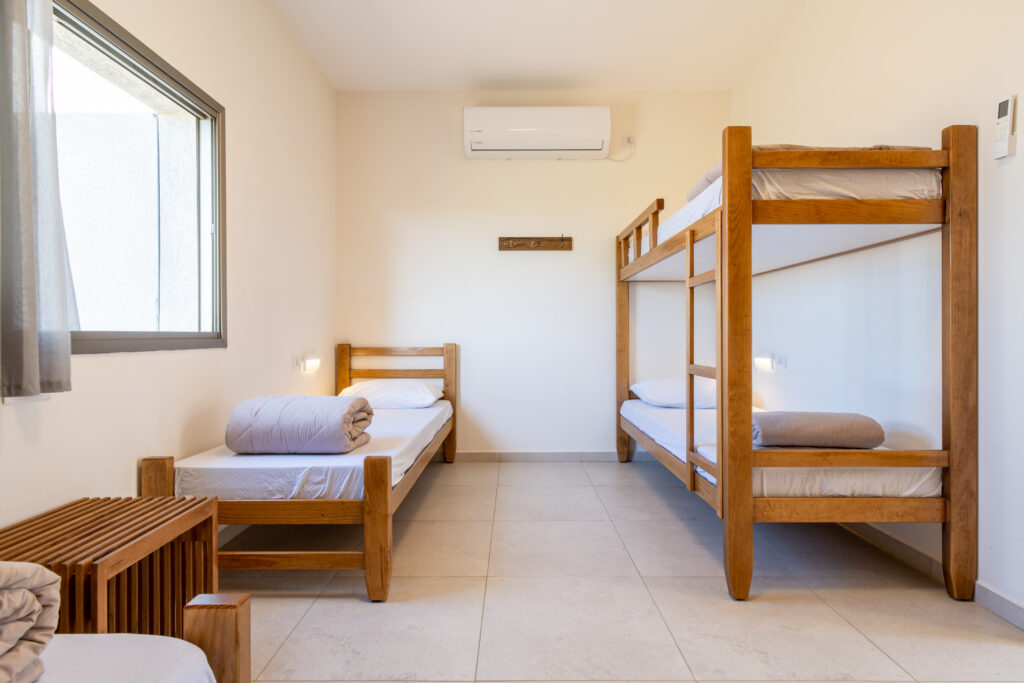 פנים חדר בבית ספר שדה אכזיב. מיטות קומותיים ומיטת יחיד ונוף מהחלון 