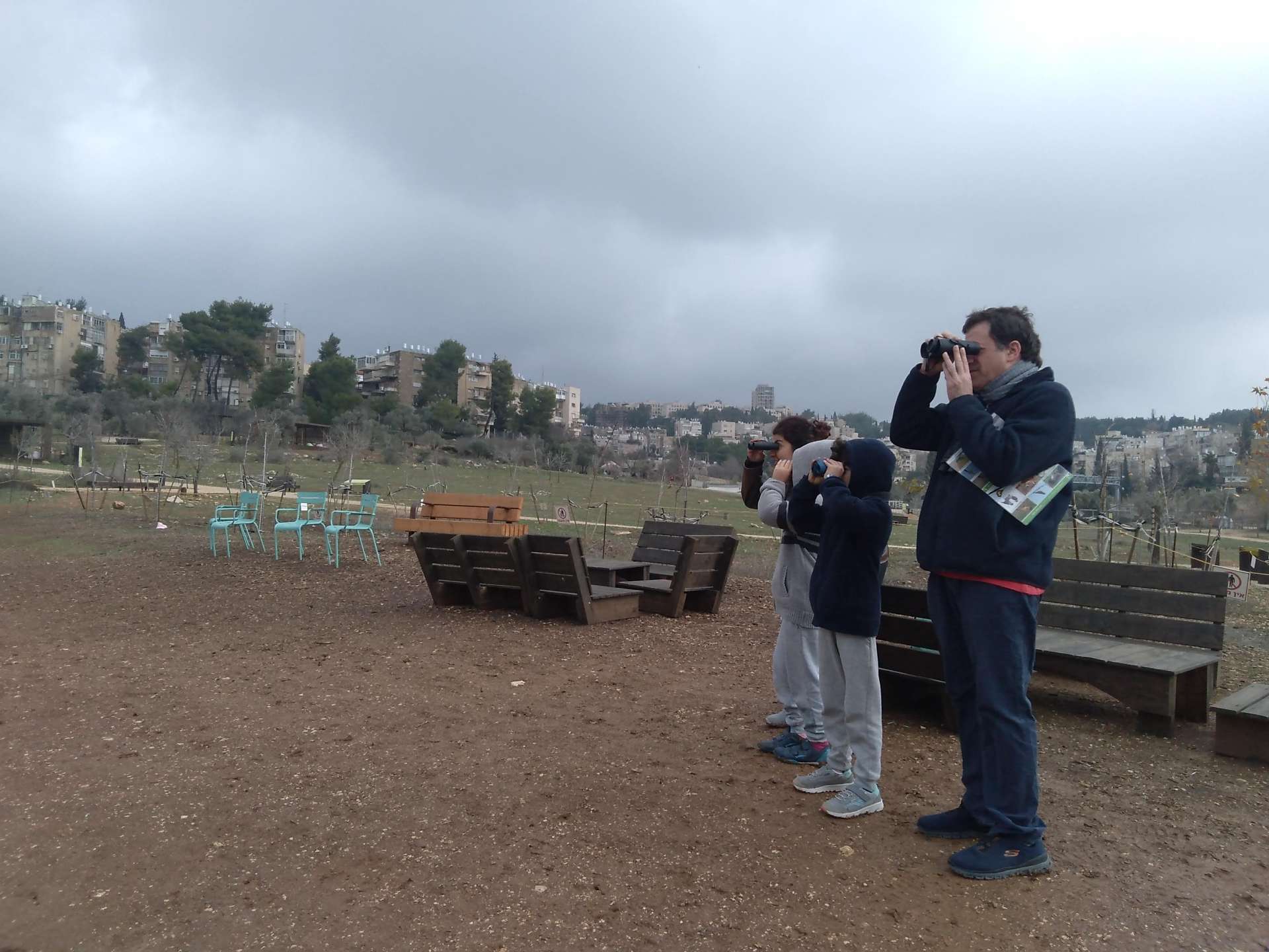 הורה ושלושה ילדים צופים בציפורים דרך משקפת