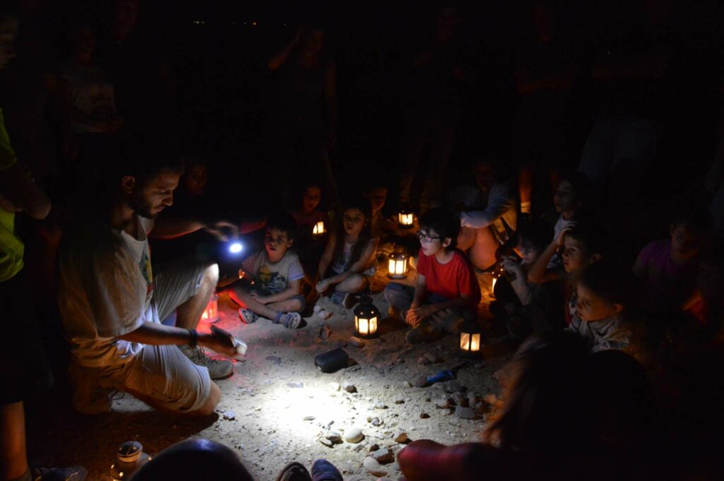 קבוצת ילדים מקשיבים למדריך בטיול עששיות בלילה 