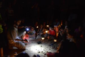 קבוצת ילדים מקשיבים למדריך בטיול עששיות בלילה