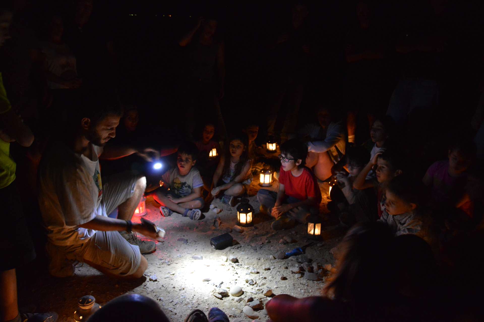 קבוצת ילדים מקשיבים למדריך בטיול עששיות בלילה