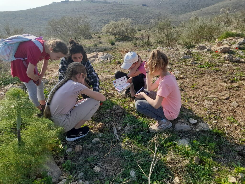 ילדים יושבים סביב פרחים עם מגדיר פרחים בפארק השרון חדרה 