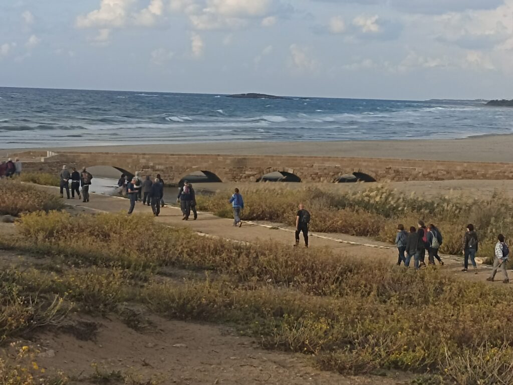 אנשים מטיילים בשפך נחל תנינים הנכנס לתוך הים בחורף 