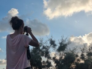מטיילת עם משקפת מביטה לעבר השמיים