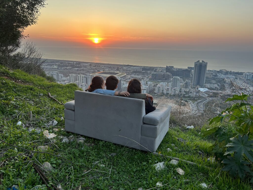 מטיילים צופים בשקיעה בטבע מעל העיר חיפה בתצפית 