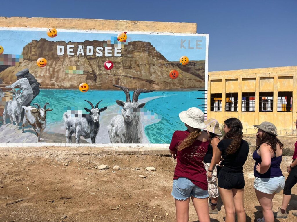 מבנה עם גרפיטי על ים המלח ובנות מסתכלות עליו 