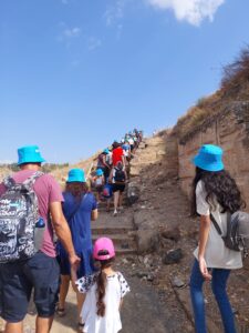 קבוצת מטיילים מבוגרים וילדים מטיילים במעלה גבעה, עולים במדרגות