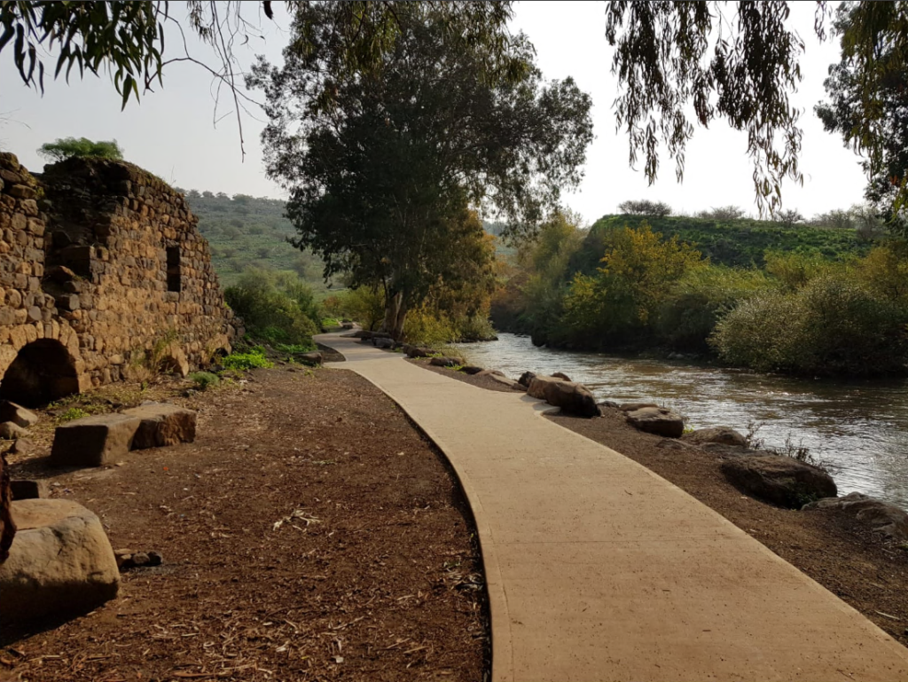 טיילת לאורך נהר, לידה מבנה עתיק ומסביבה עצים 