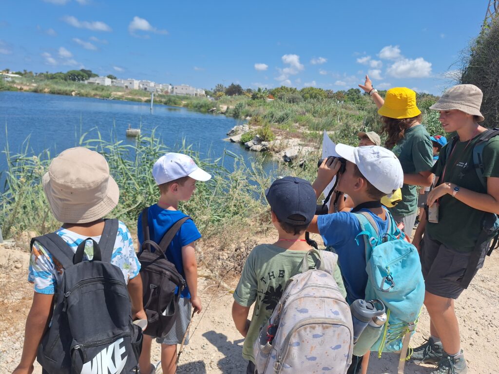 ילדים בקייטנת קיץ בטיול צפרות במעגן מיכאל עם משקפות 