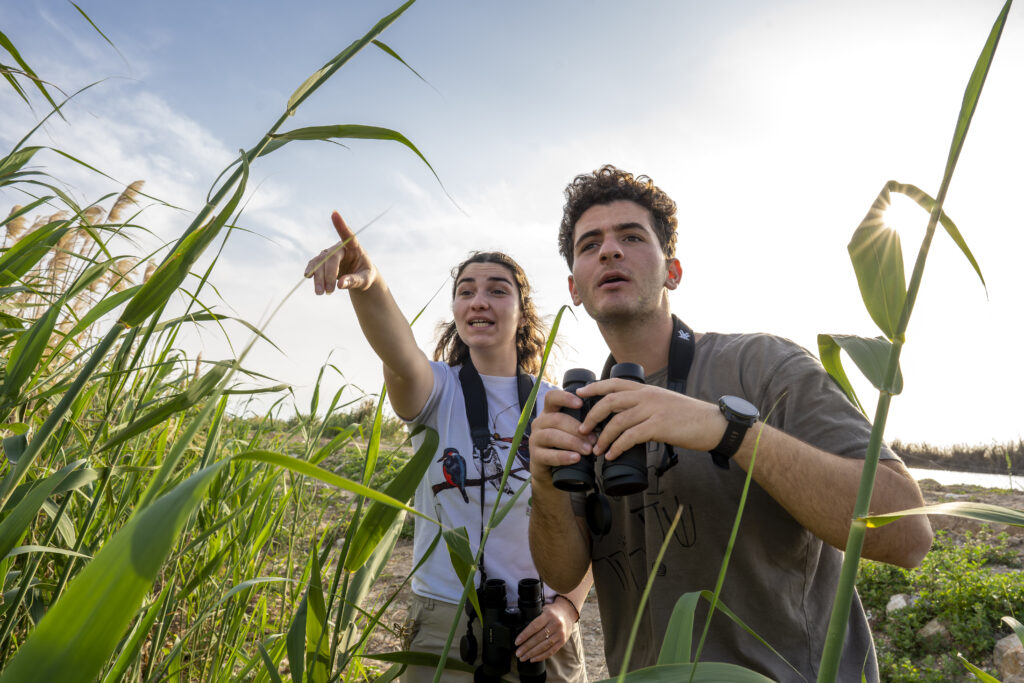 מטיילים בפארק הצפרות עם משקפות מחפשים ציפורים