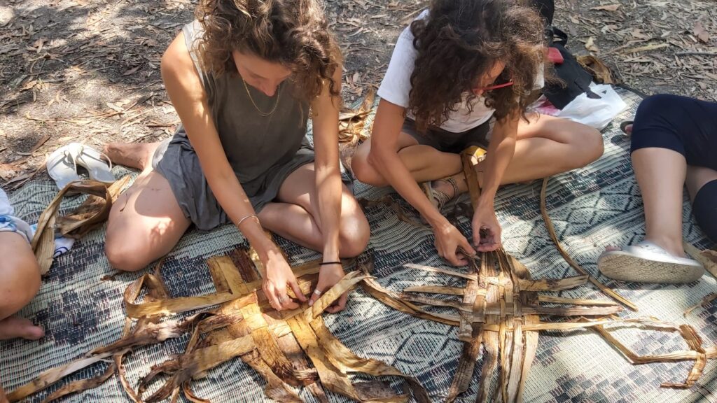 נערות קולעות מחומרי הטבע בסדנת מלאכות קדומות