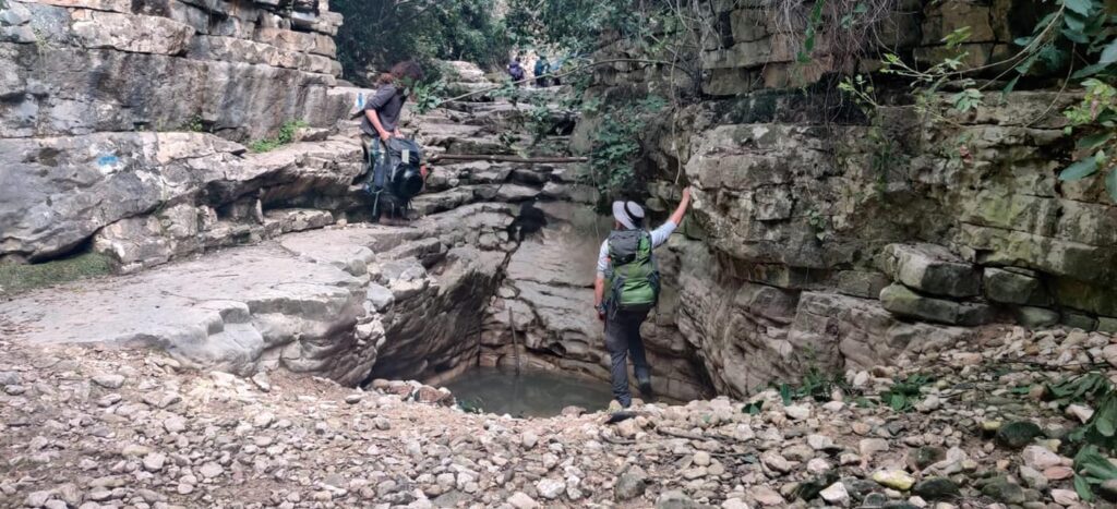 מטיילים בנחל בוסתן ליד בריכת מים קטנה 