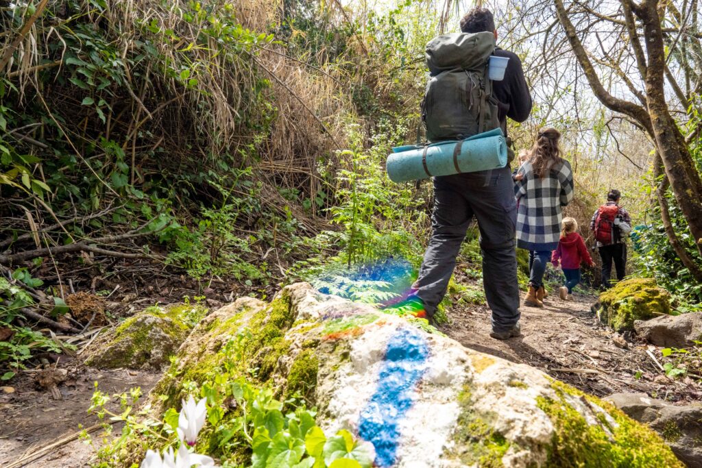 סימון שביל בתקריב ומלפניו משפחה מטיילת ברמת הגולן 
