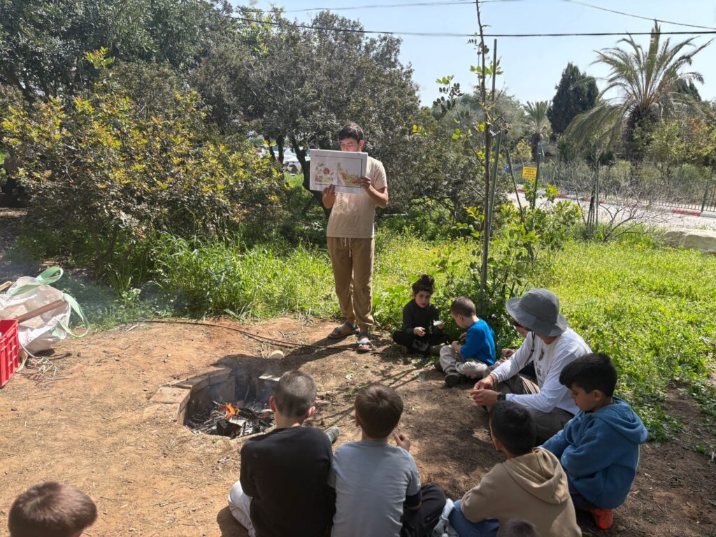 מעגל ילדים עם מדריך סביב מדורה בבית ספר שדה חוף כרמל בזמן מלחמה 