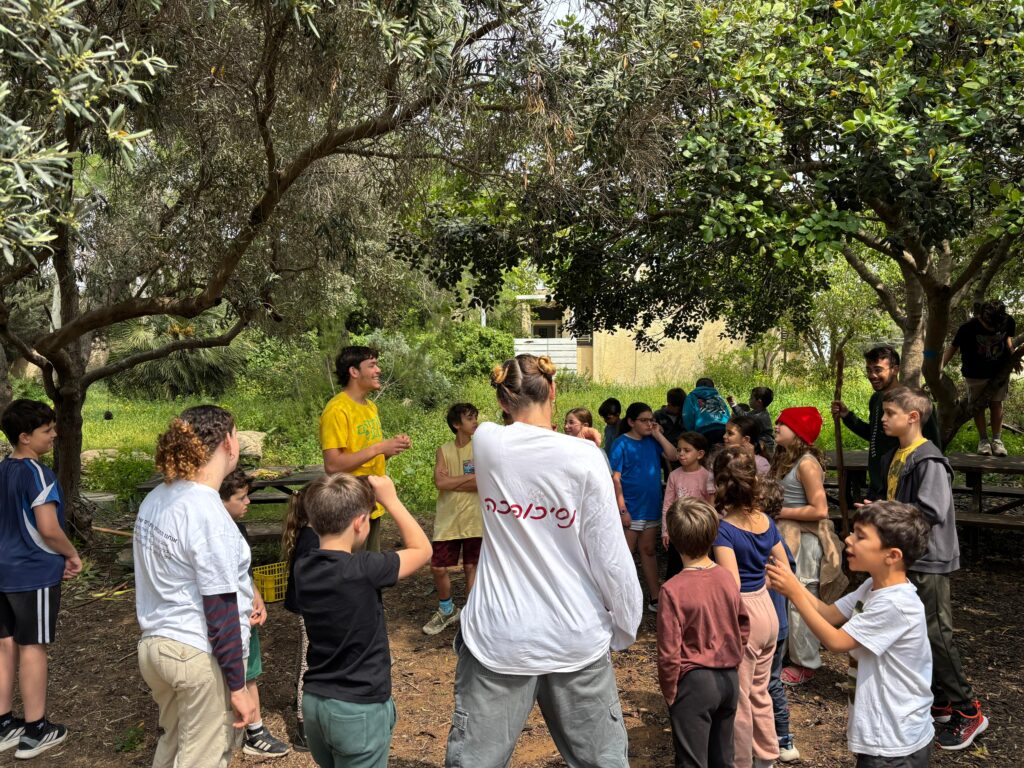 מעגל ילדים ומדריכים בפעילות בחוץ בבית ספר שדה חוף כרמל בזמן מלחמה 