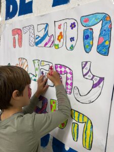 ילד צובע בפעילות יצירה בבית ספר שדה חוף כרמל ליד מקלט