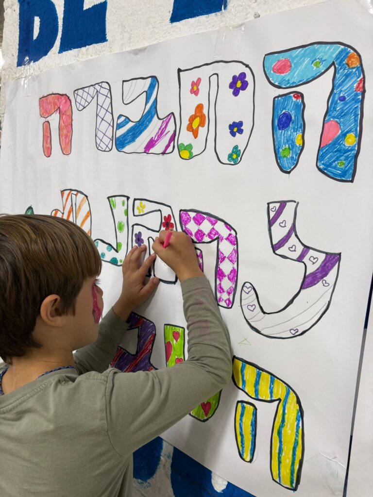ילד צובע בפעילות יצירה בבית ספר שדה חוף כרמל ליד מקלט 