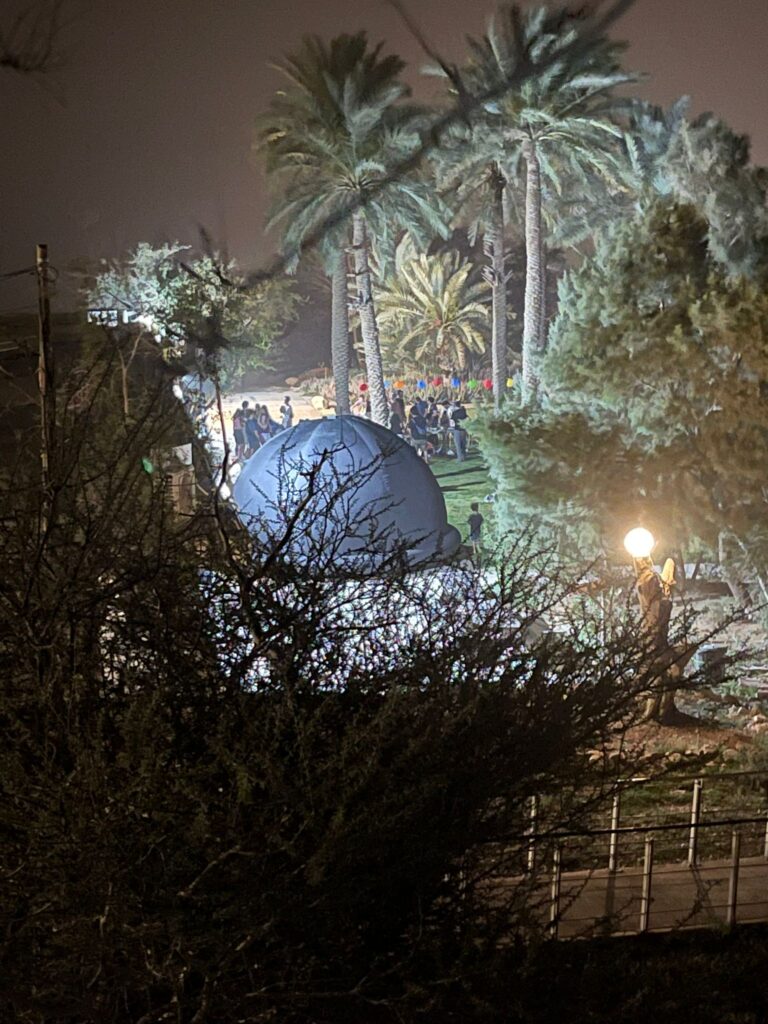 צילום מרחוק של הפלנטריום הקטן והמתקדם שלנו בין הצמחיה בפסטיבל ים המלח 2030 בעין גדי 